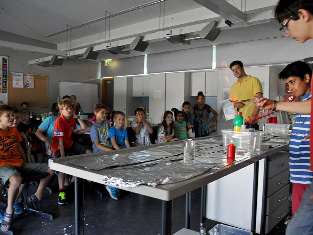 Kinder arbeiten an einem langen Experimentiertisch im Fachraum.